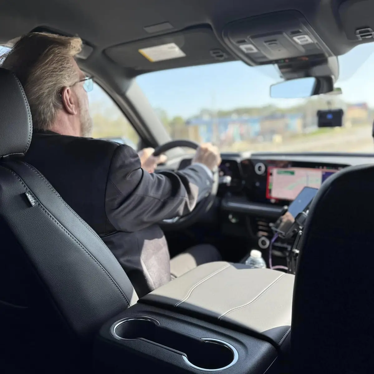 Chauffeur driving a vehicle with a GPS screen visible on the dashboard.