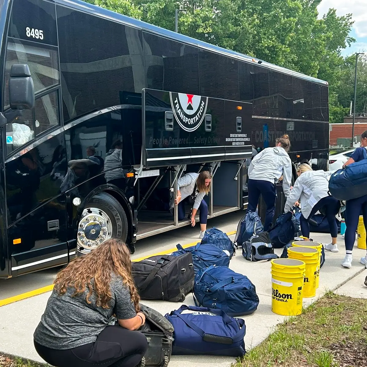 A group of people unloading gear from an Echo East Coast Transportation motorcoach.