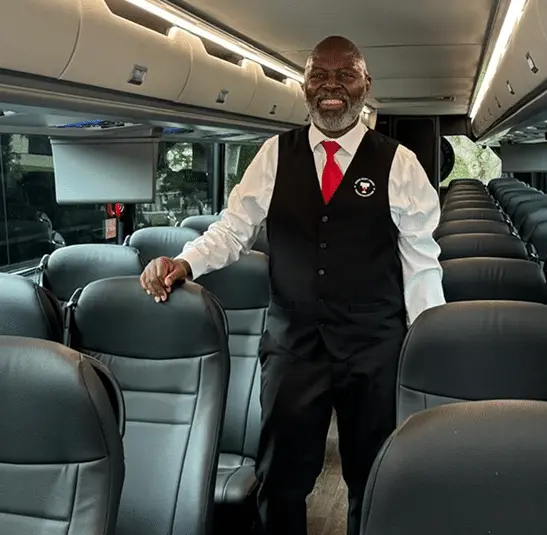 Chauffeur standing in the aisle of a coach bus.
