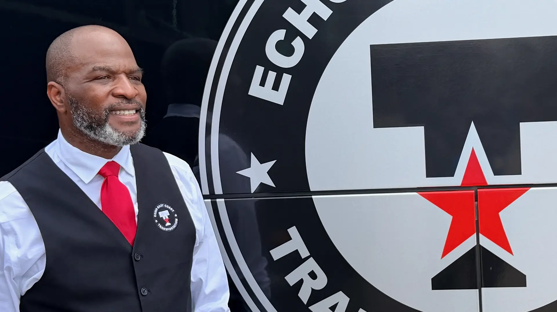 Chauffeur standing beside the Echo East Coast Transportation logo on a bus.