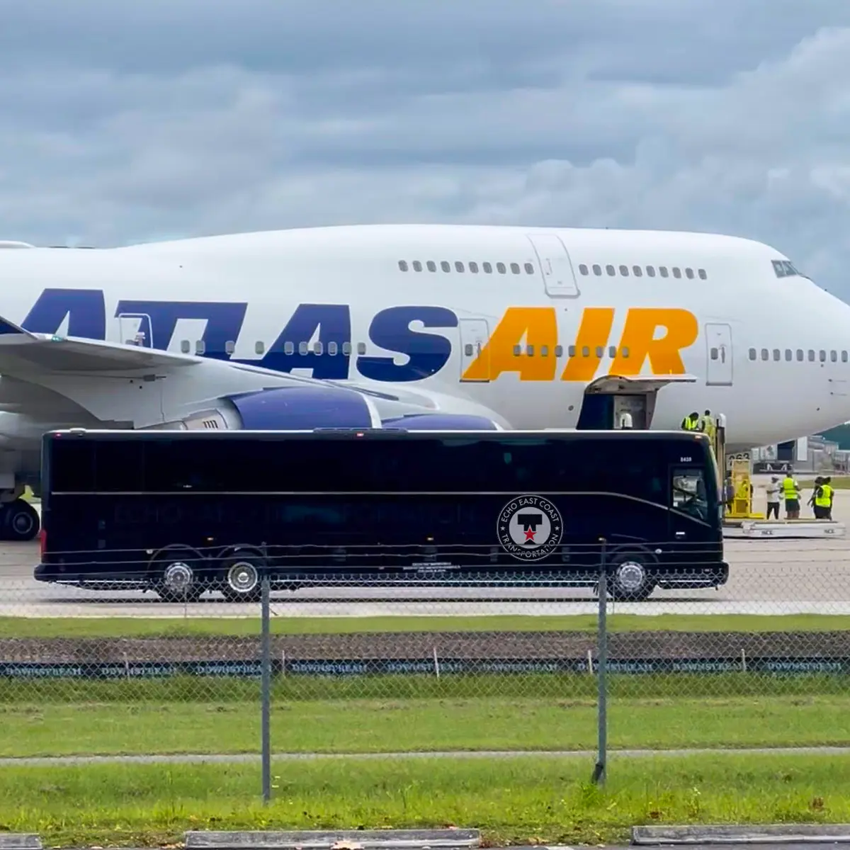 ECHO East Coast Transportation motorcoach parked on the tarmac beside an Atlas Air cargo jet.