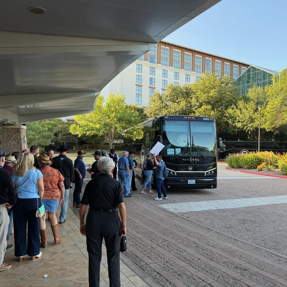 Passengers boarding an Echo East Coast Transportation motorcoach outside a hotel.