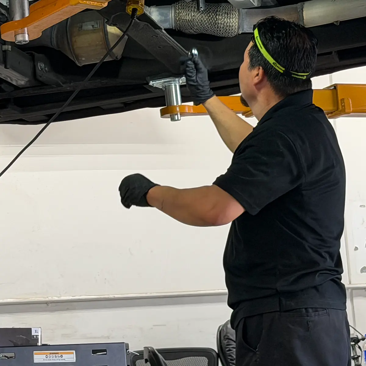 Mechanic working on the underside of a vehicle on a lift.