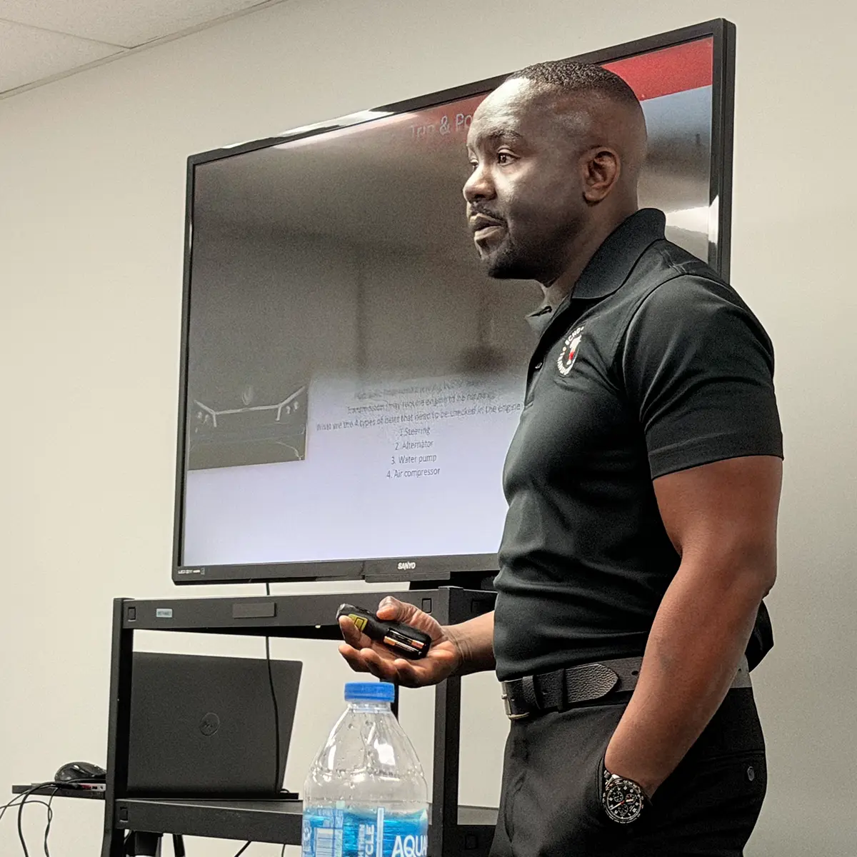 Trainer presenting a vehicle maintenance training slide.