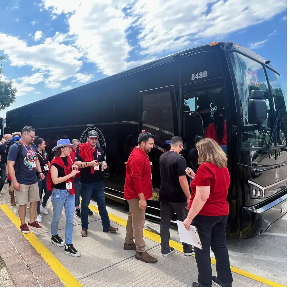 Group of attendees in red shirts boarding an Echo East Coast Transportation bus.